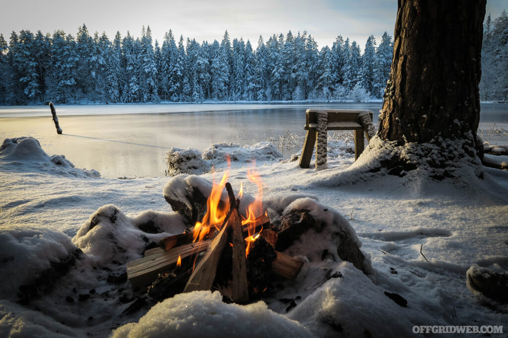 Scenic photo of a winter campfire next to a frozen lake