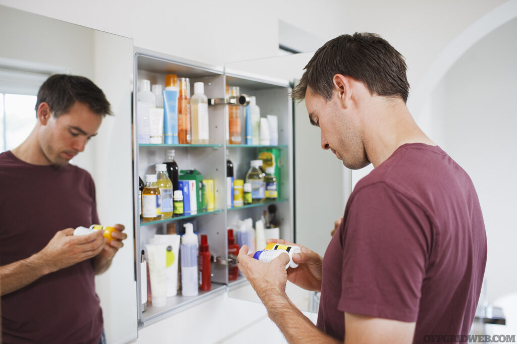 Photo of an adult male inspecting the contents of his medicine cabinet after receiving survival medicine suggestions.