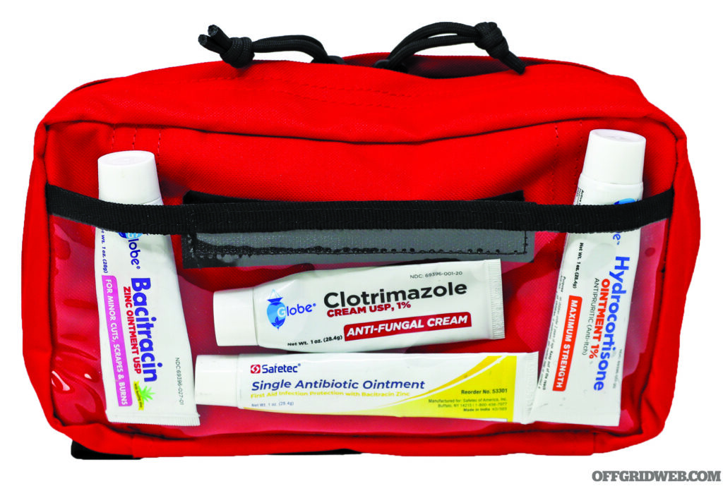 Studio photo of a red med pouch containing several over the counter topical ointments.