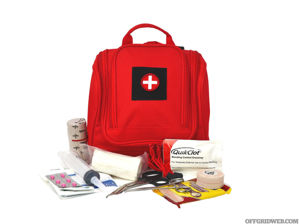 Studio photo of a red first aid kit with its contents stacked around it for survival medicine suggestions.