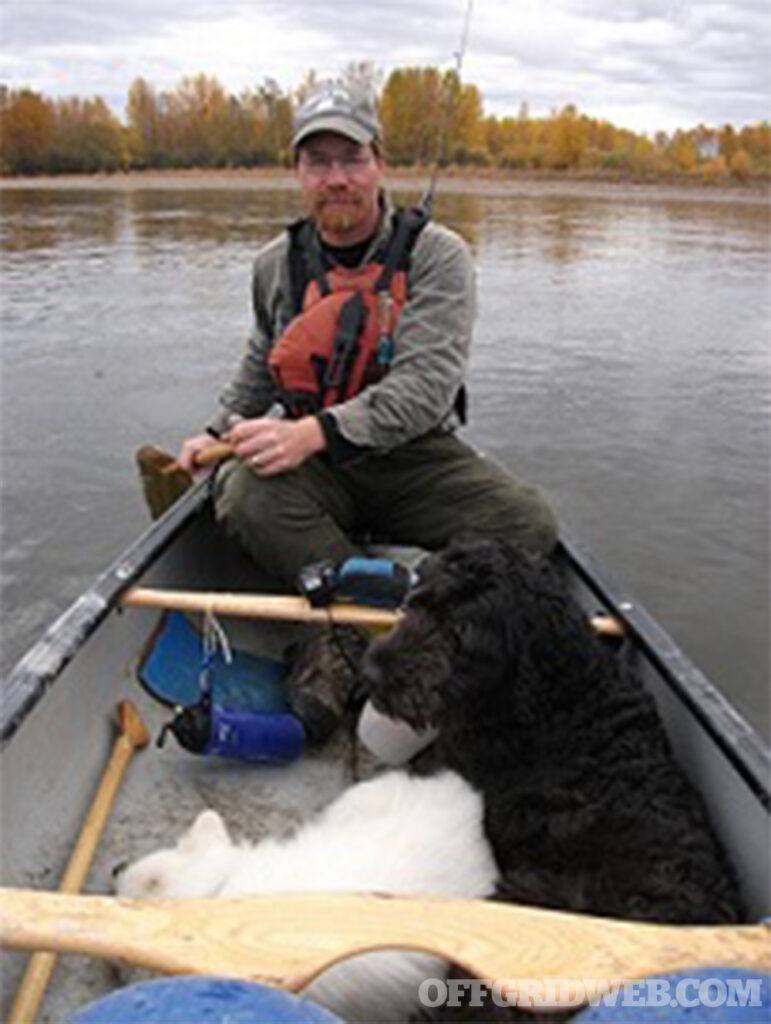 Photo of Kelly Harlton sitting in a canoe with his dog.