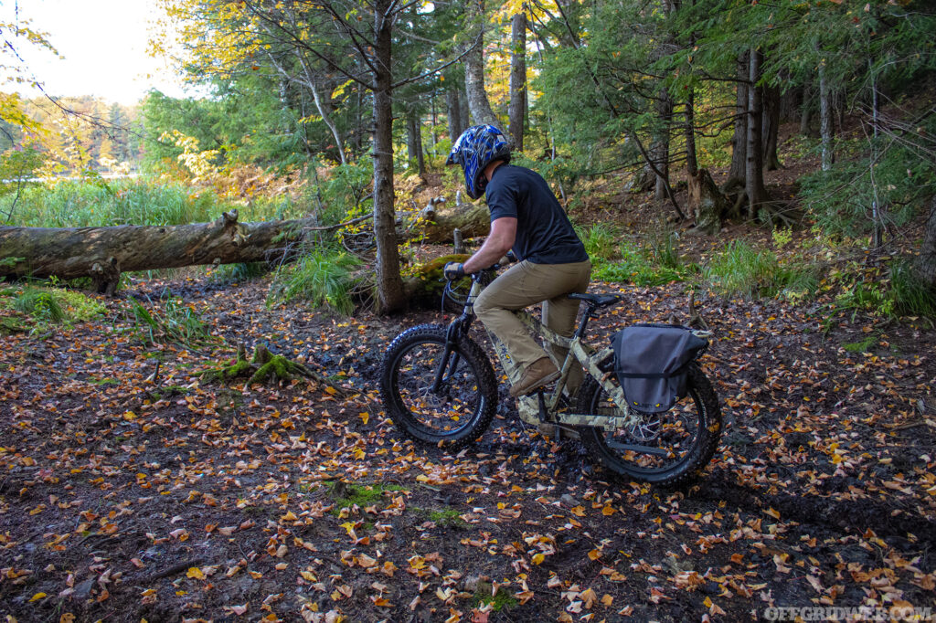 Photo of an adult male riding a fat-tire eBike through thick mud.