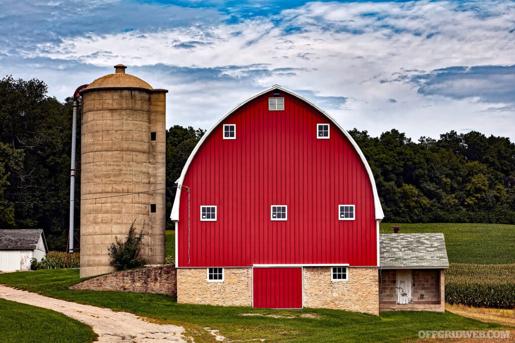 Photo of the side of a red barn and silo out in the countryside.