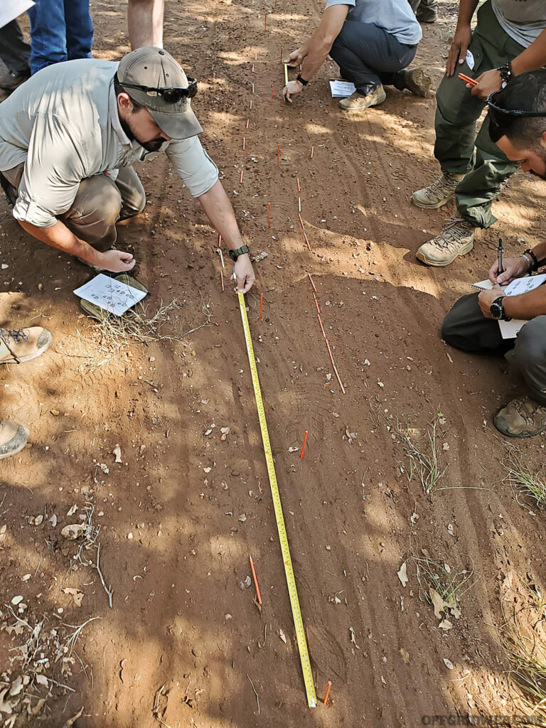 Photo of students measuring the distance between steps in a spoor pit during Craig Caudill's Tracking Fundamentals class.