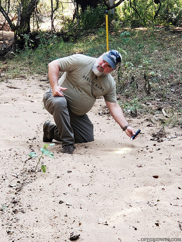 Craig Caudill using a flashlight to demonstrate how the angle of overhead light, such as the sun, affects the contrast of a footprint.