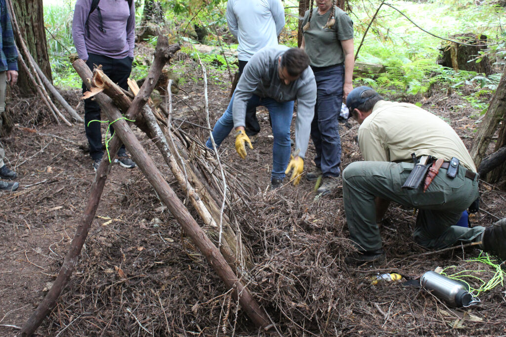 Students help pack insulation along the walls of an A-frame debris shelter.