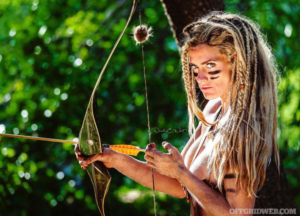 Photo of Naked and Afraid contestant Melissa Miller holding a primitive bow.