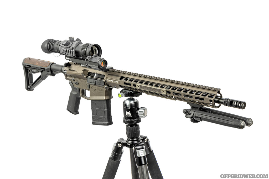 Studio photo of an armasight thermal optic mounted on a stag arms rifle mounted on a tripod.