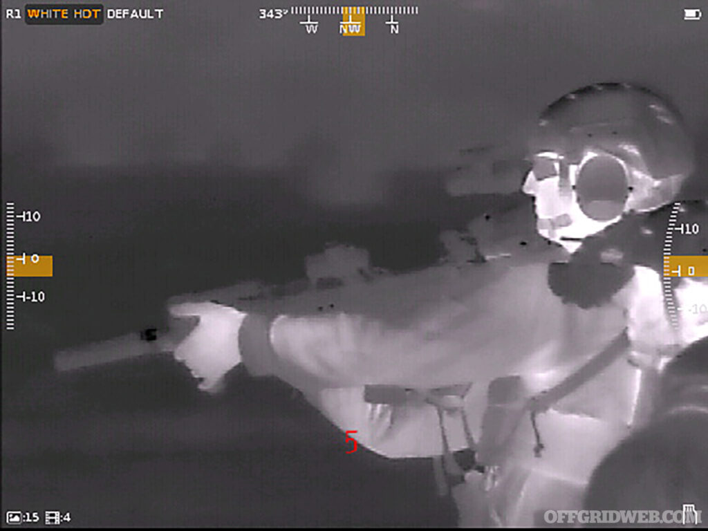 Thermal optic image of a man holding a cold suppressed rifle.