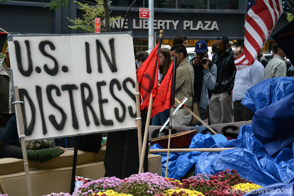 Photo of a sign amongst a protesting crowd that reads 