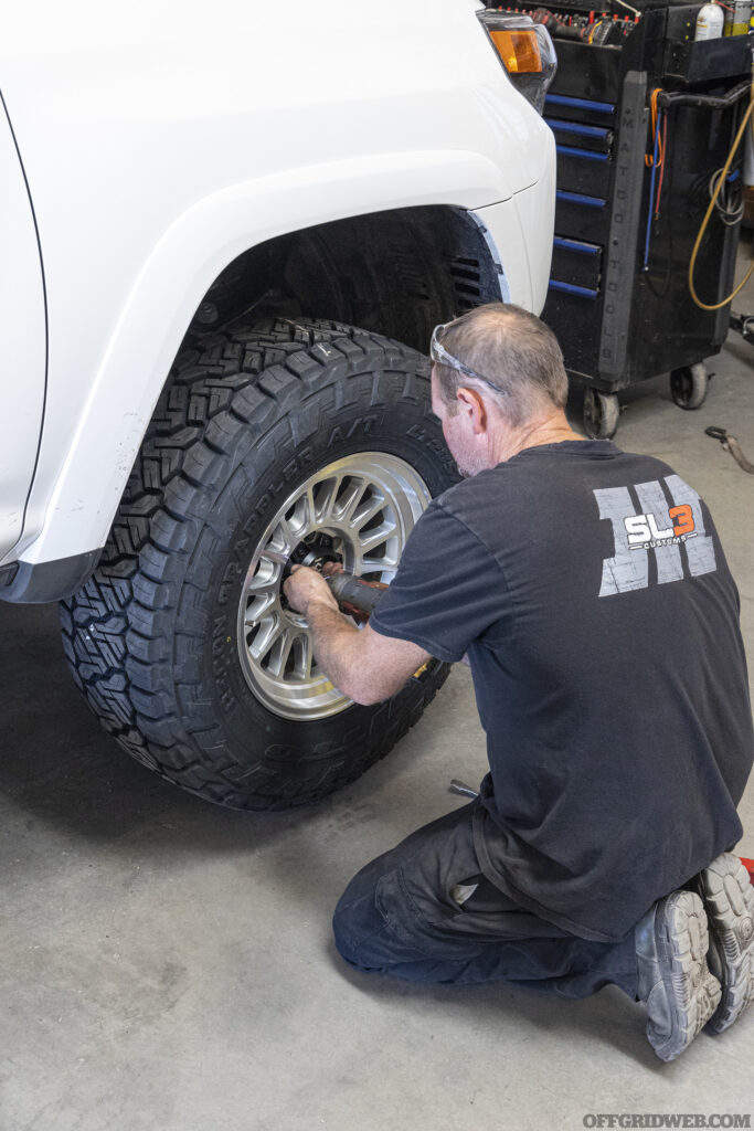 Mechanic installing a tire back onto a toyota 4runner.