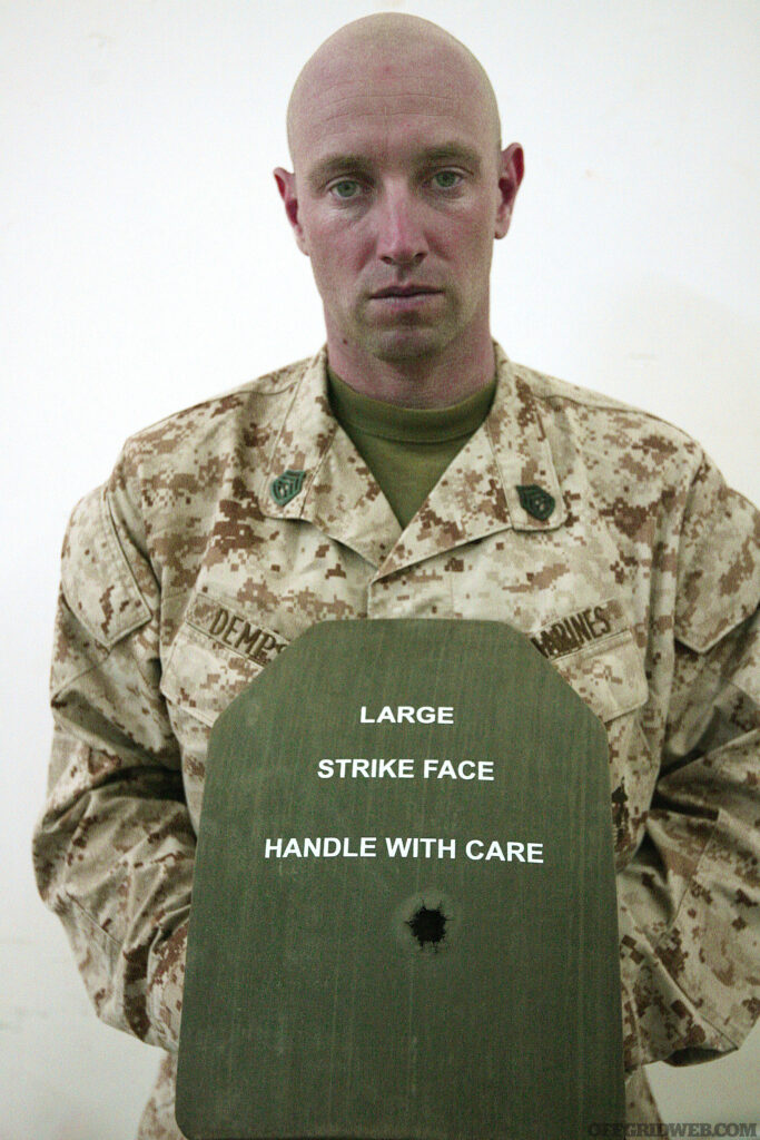 Gunnery Sgt. Sean M. Dempsey, a platoon commander from Jersey City, N.J., assigned to Weapons Company, 2nd Battalion, 8th Marine Regiment, Regimental Combat Team 5, shows off the bullet hole in his small-arms protective insert. Dempsey was shot in the back by an insurgent and walked away with only a bruise on his back.