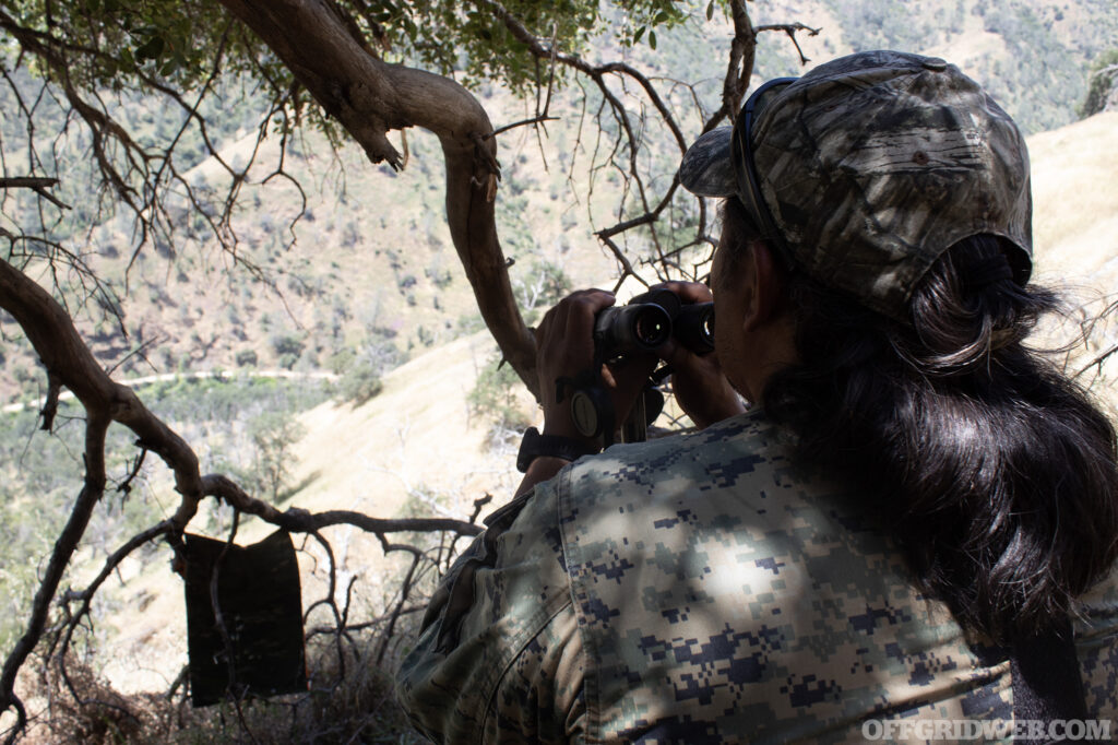 An instructor looks over a mountain valley from an elevated position.