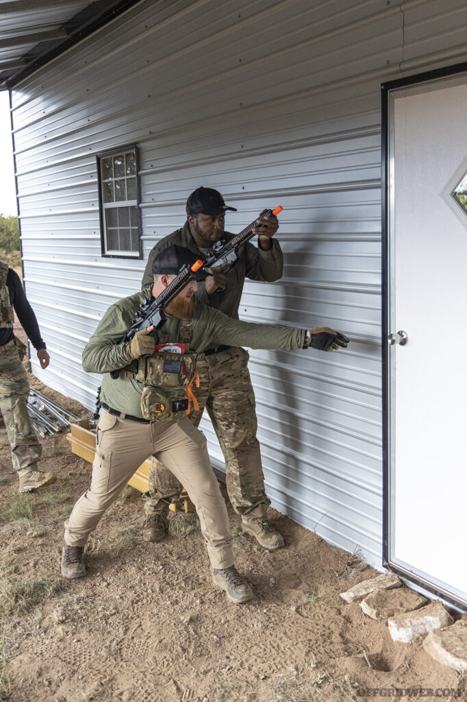 Two adult males train to clear a room with firearms.