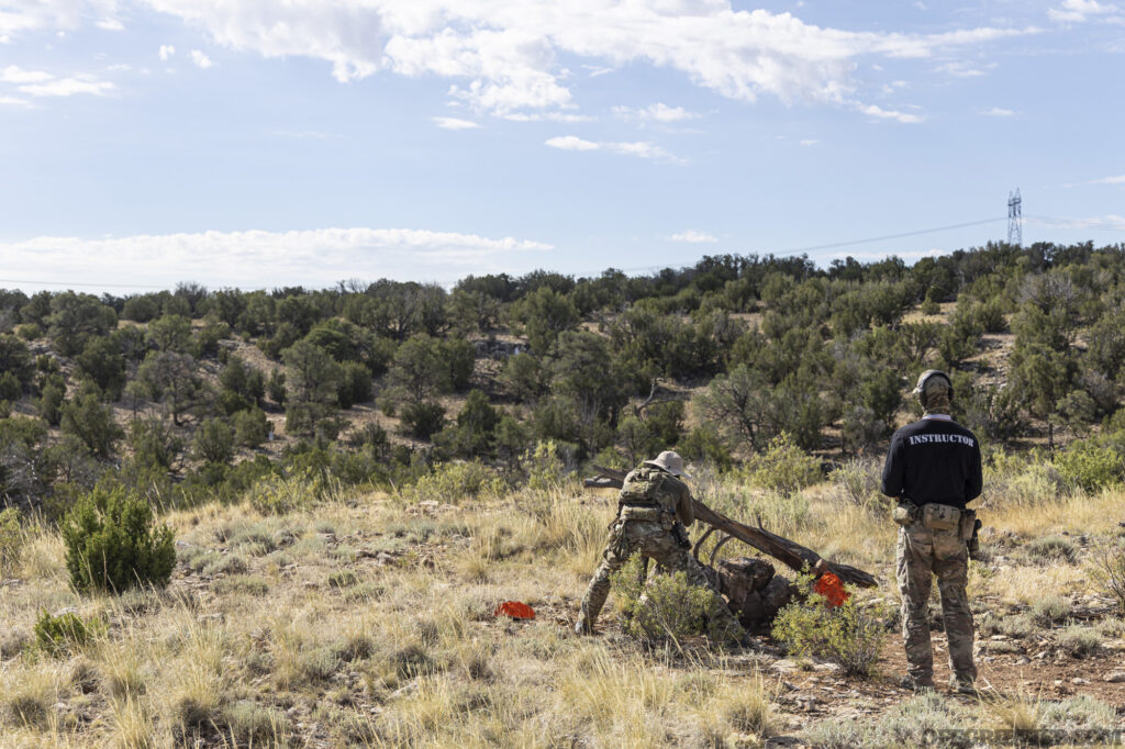 An adult male takes aim at a target in the distance at BRVO Tactical's range.