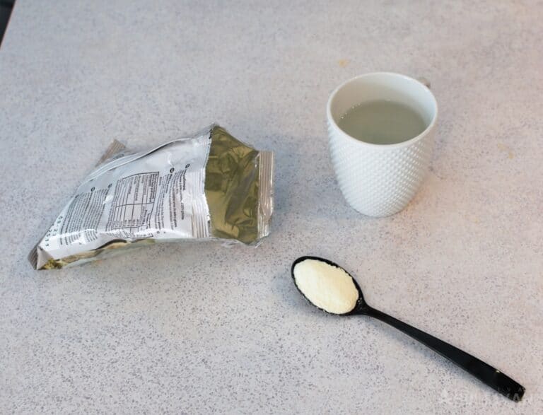 tablespoon of powdered milk next to package and cup of water