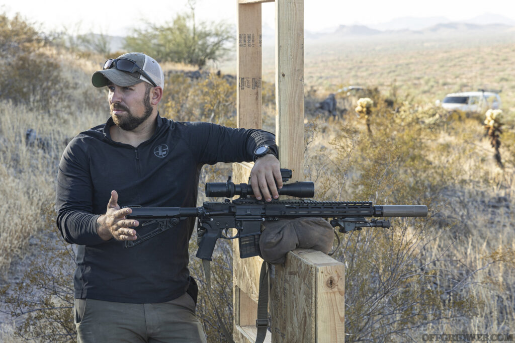 Photo of an adult man standing with a scoped carbine while he explains scoped carbine fundamentals.