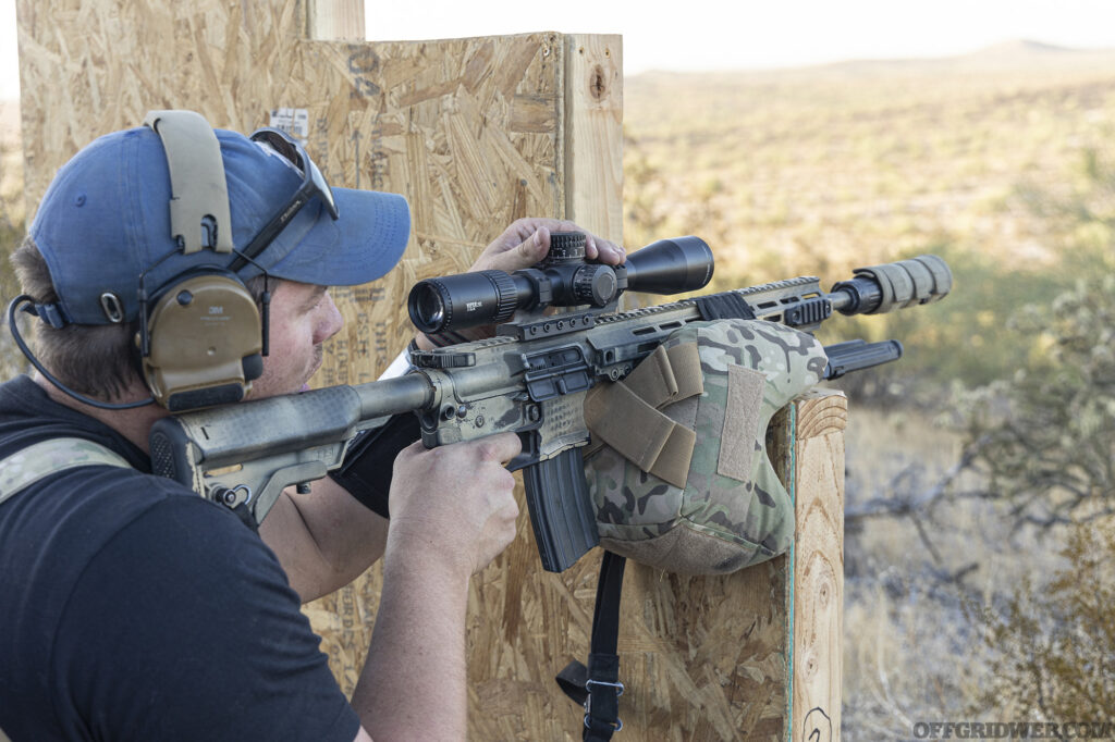 Photo of a man adjusting the scope mounted to his carbine.