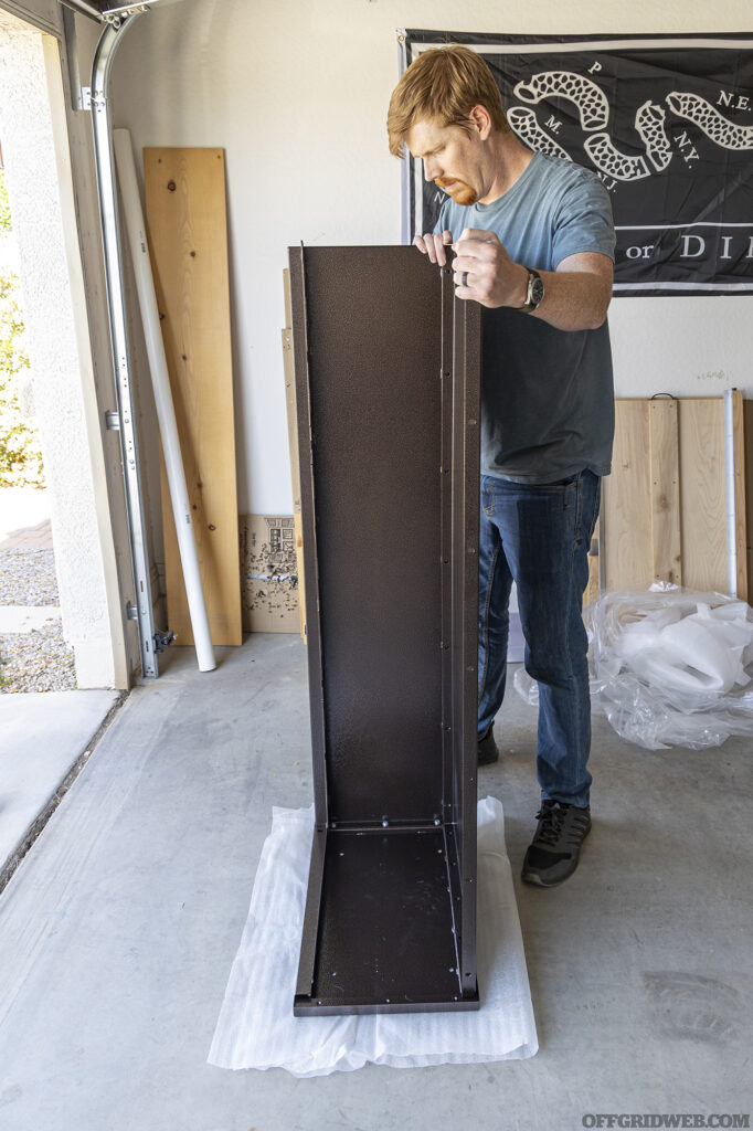 An adult male assembling the gun cabinet.