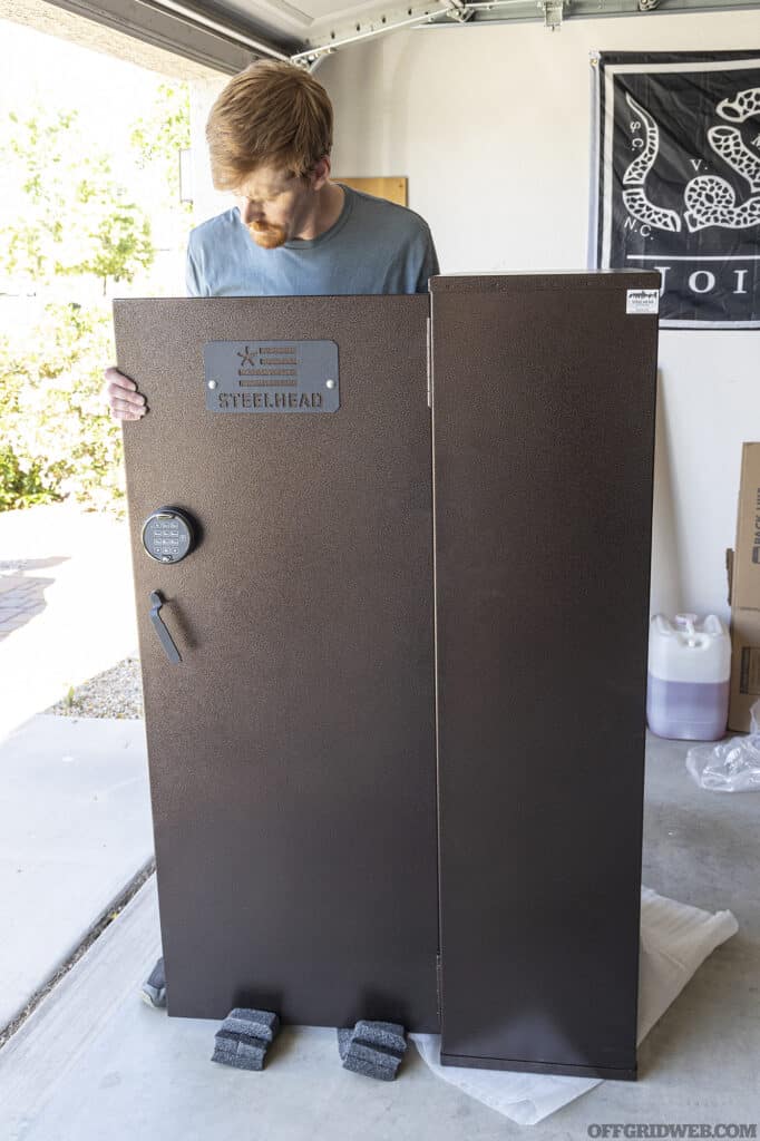 An adult male installing the door on a Steelhead Outdoors Scout 25 gun cabinet.