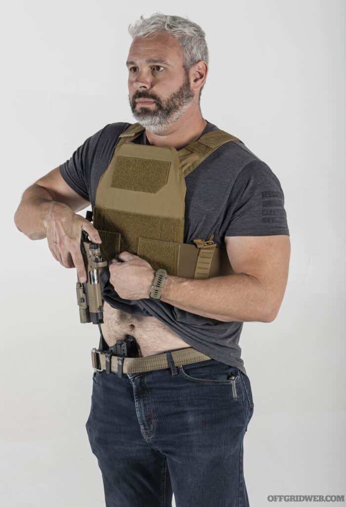 A man wearing haley strategic's INCOG plate carrier drawing an appendix carried handgun.