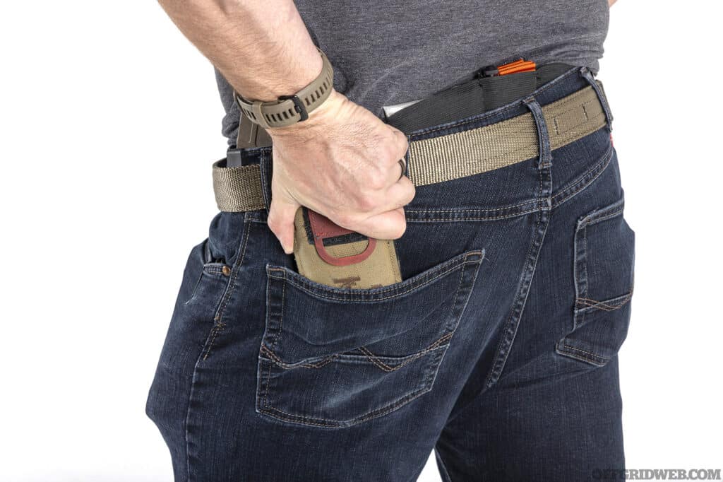 Studio photo of man pulling a low vis tourniquet out of his back pocket.