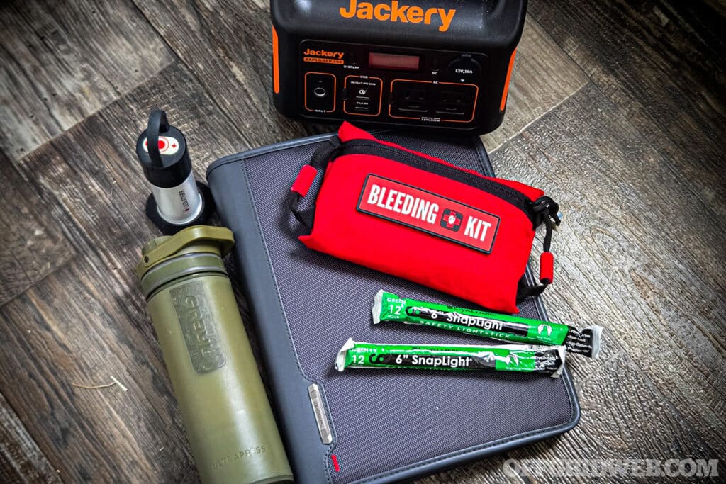 image of binder, bleeding kit, grayl water filter, chem lights, lantern, and solar generator