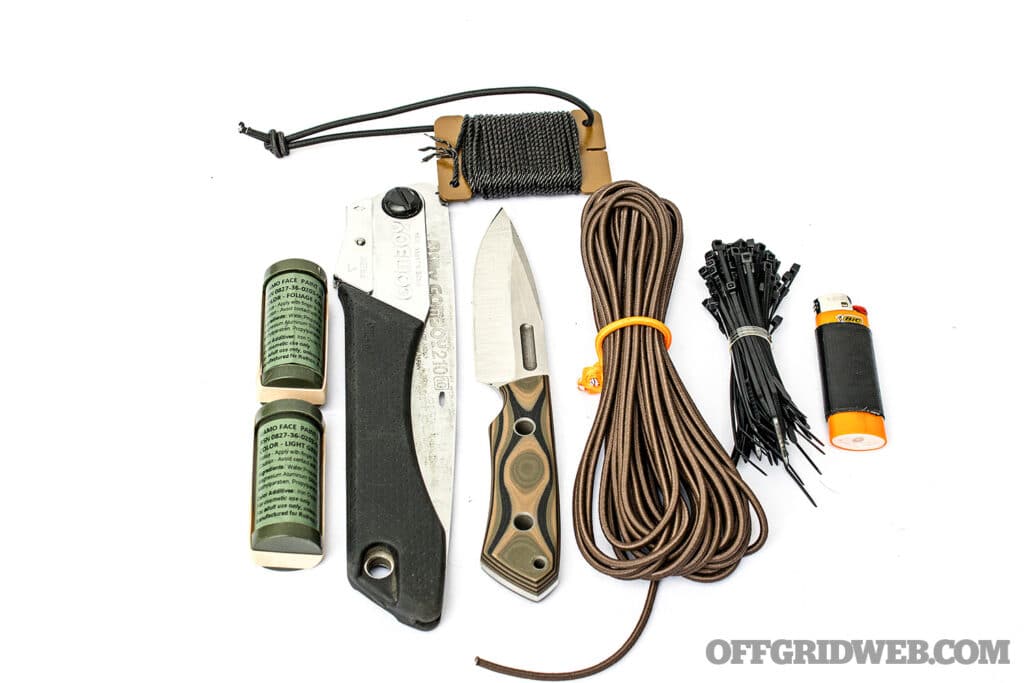 Image of small tools including a fixed blade knife, folding saw, lighter, and assorted cordage