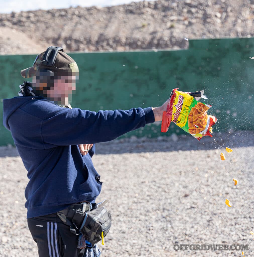 man firing a wheelgun through a bag of chips