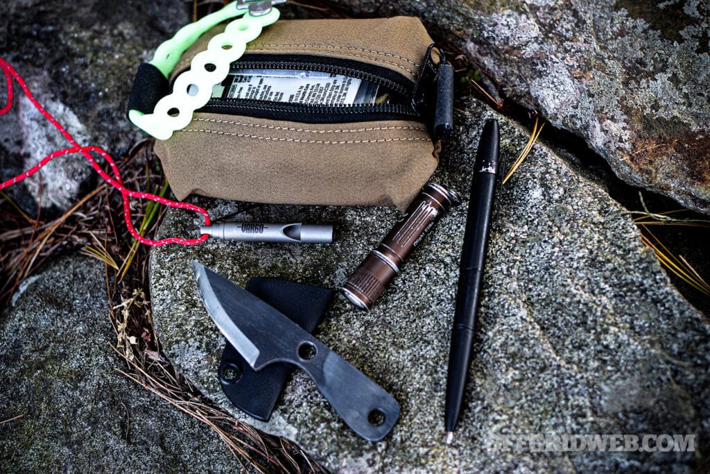 Image of a pouch and small tools outside of a mini survival kit