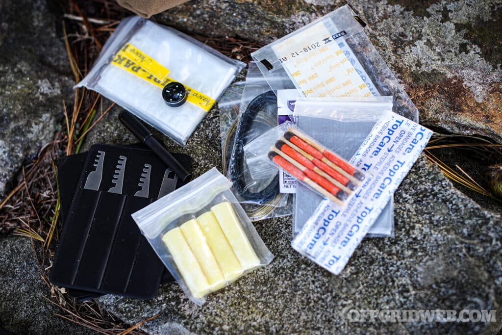 assorted fires starting and emergency supplies from the inside of a mini survival kit