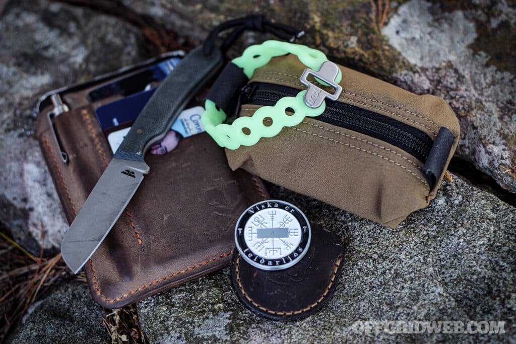 Image of a mini survival kit along with everyday carry items