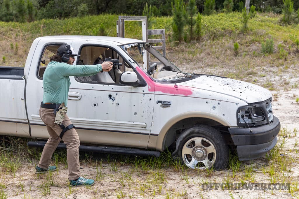 image of a man with a hand gun safariland holster behind a pickup truck during the full spectrum warrior course