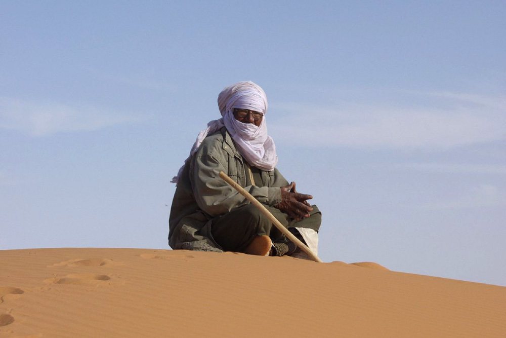 Man sitting on top of a sand dune.