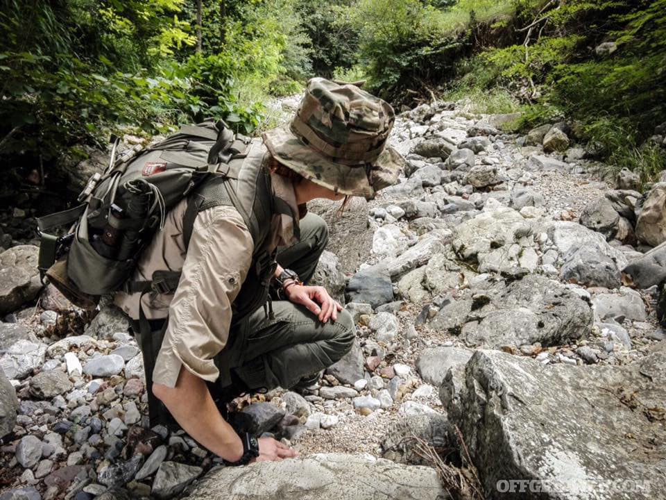 author navigating rough terrain in a chest rig